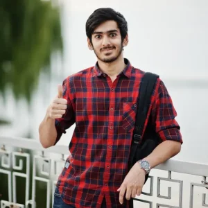 young-student-man-checkered-shirt-jeans-with-backpack-posed-evening-city-against-lake-shows-thumb-up_151355-5271